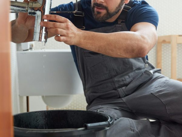 male-plumber-working-to-fix-leaking-sink-in-home-bathroom.jpg