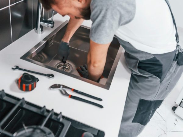young-professional-plumber-in-grey-uniform-working-on-the-kitchen.jpg